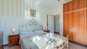 A bedroom with a bed, wooden wardrobe, and a nightstand with a lamp. - Casa Vittoria 800m from sea (Forte dei Marmi)