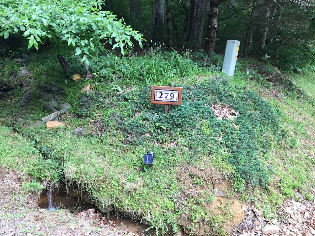 A natural setting with a sign displaying the number 279, a solar-powered device, and a small stream.