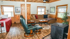 A cozy room with a wooden ceiling, a sofa, a chair, a table, a bed, and a fireplace. - Touche' Too Cabin by Buffalo Mtn Getaway (Meadows of Dan)