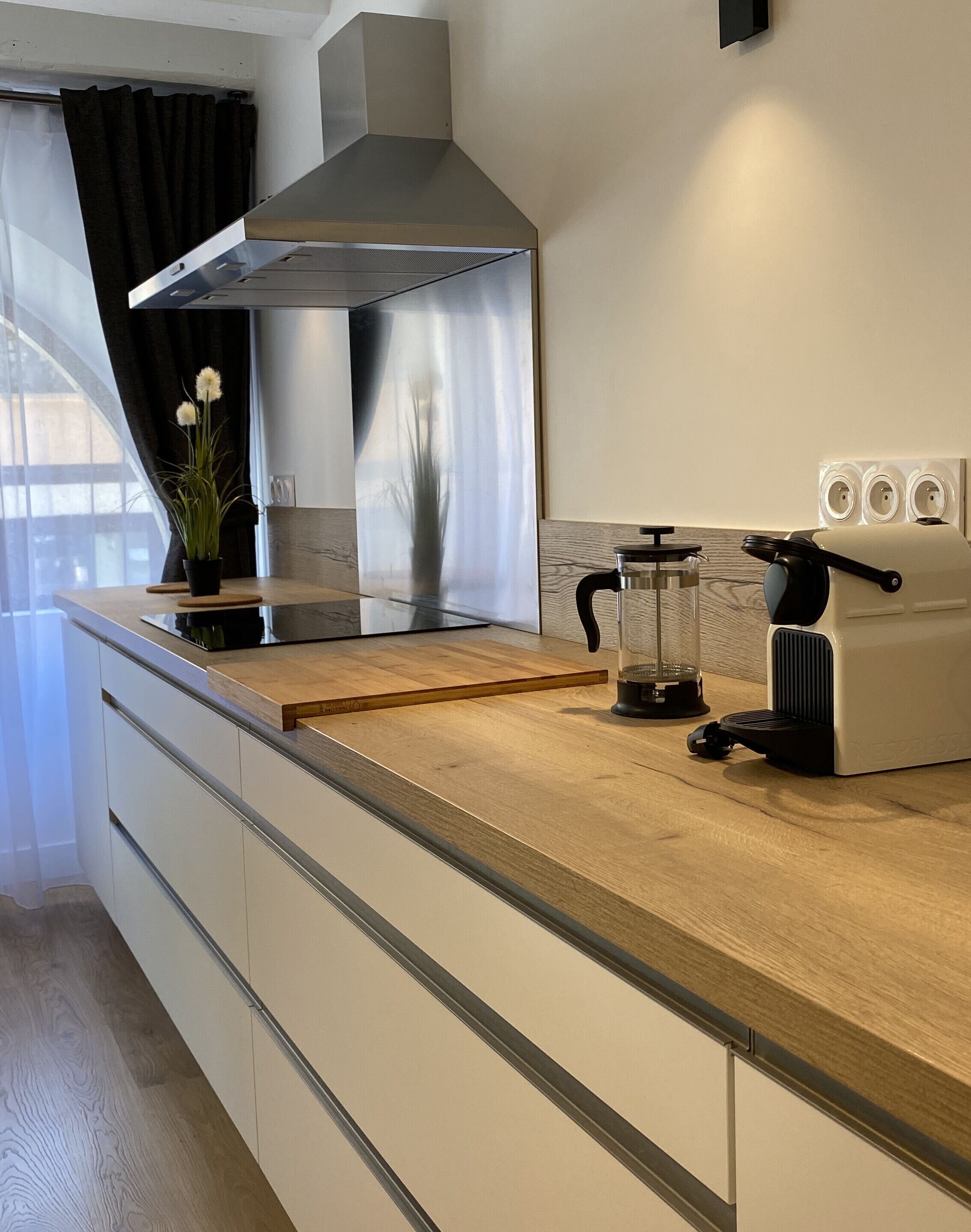 Una cucina moderna con cappa in acciaio inossidabile, forno a incasso e macchina da caffè.