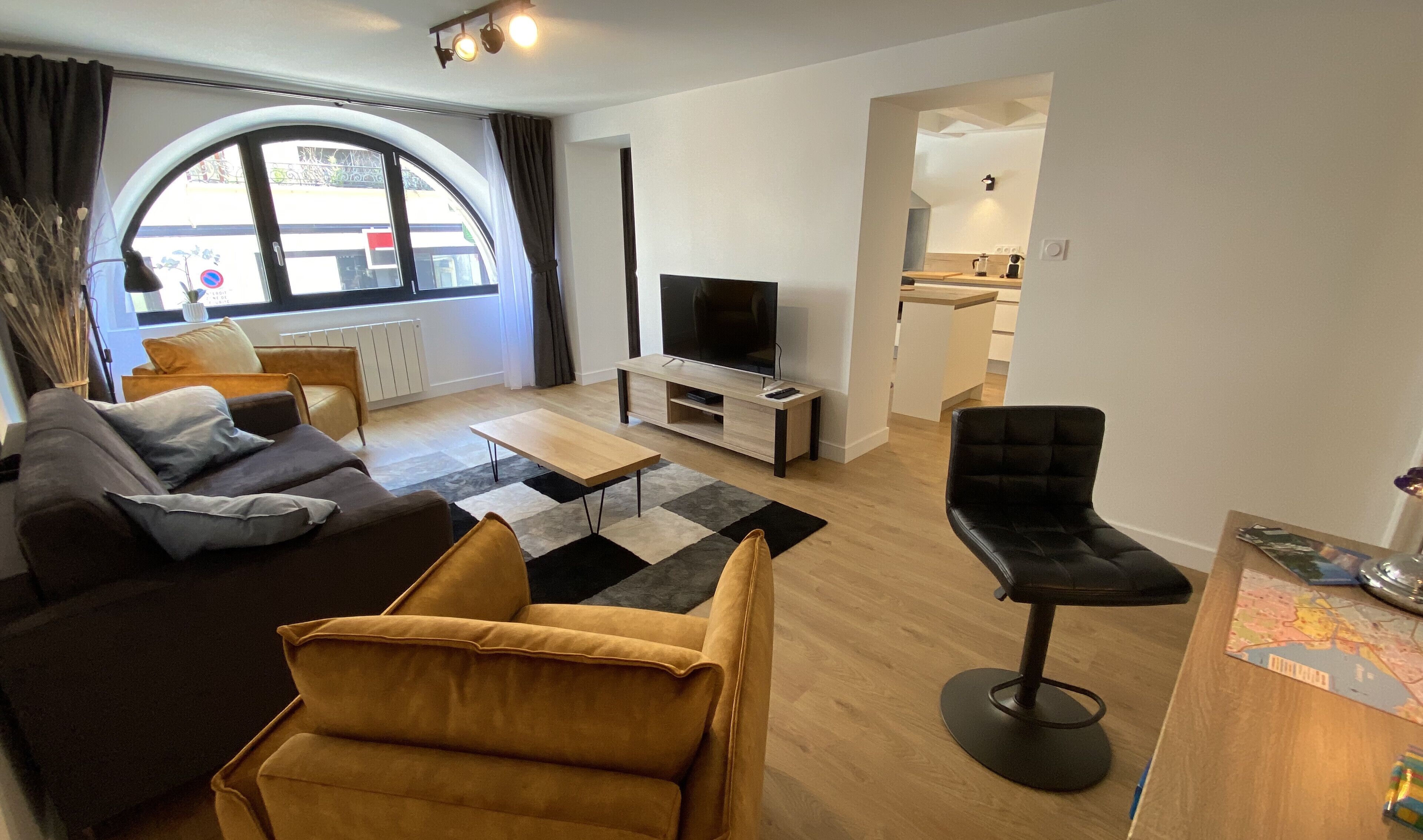 A modern living room with a sofa, a coffee table, a TV, and a dining area.