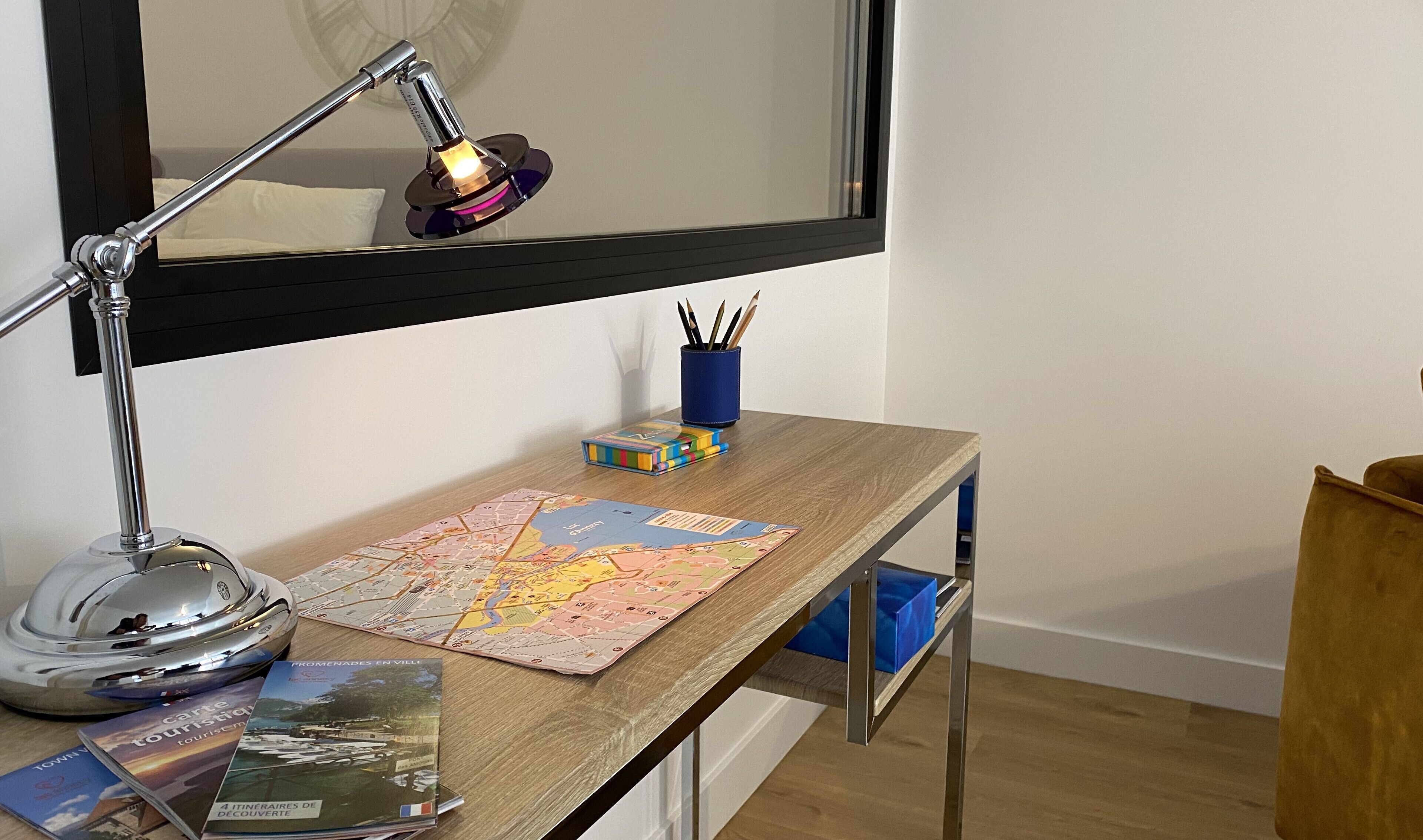 Un escritorio de madera con un mapa, una lámpara y un portalápices azul.