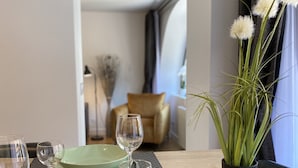 A dining table with green plates, wine glasses, and a potted plant.