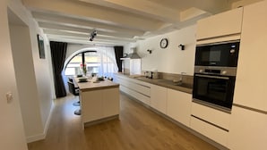A modern kitchen with white cabinetry, a wooden island, and built-in appliances including a microwave and oven.