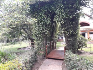 A wooden pathway leading to a covered area with a bench. - Quinta La Gardenia (Puembo)