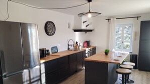 Una cocina moderna con una isla central, electrodomésticos de acero inoxidable y un amplio ventanal que proporciona luz natural.