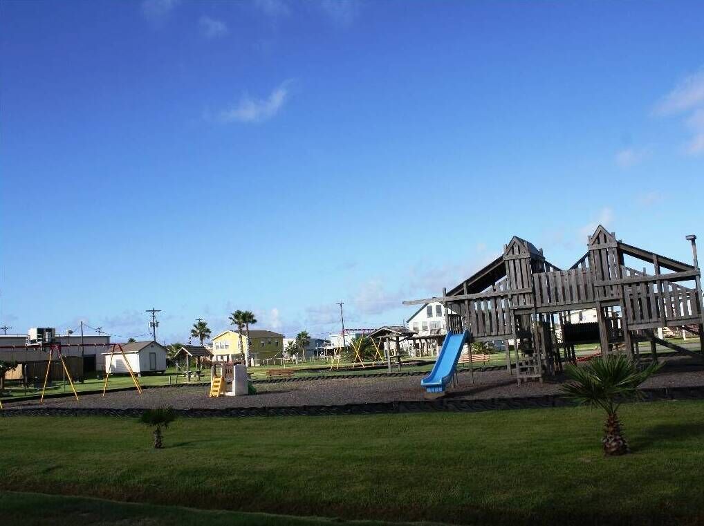 A playground with a blue slide and a wooden climbing structure.