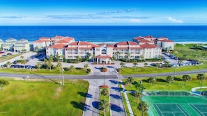 A coastal hotel with multiple buildings, a parking lot, and a tennis court. - Spacious OceanView Condo with a Balcony - VillaCapriani Resort - Up to 10 Guests (North Topsail Beach)