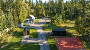 A rural property with a gravel driveway leading to a main house, a smaller cabin, and a barn.