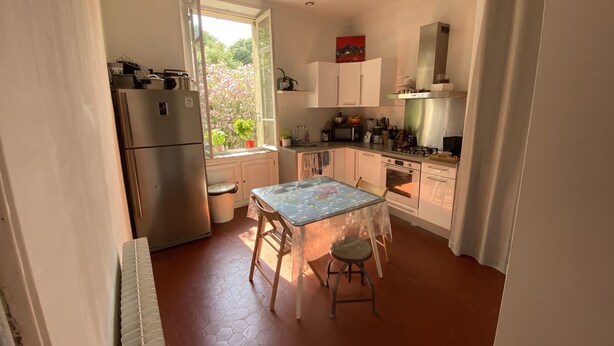 Une cuisine compacte équipée d’un réfrigérateur, d’une cuisinière et d’un évier. Une fenêtre offre une vue sur la verdure environnante.