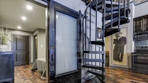 A modern interior with a staircase, a bed, and a kitchen area. - Lincoln’s Loft - Speakeasy Suite (Lincoln)