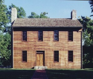 Une maison en bois à deux étages, dotée d’une porte centrale et de nombreuses fenêtres.