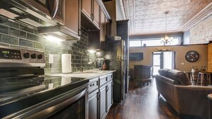 A modern kitchen with a stainless steel stove, black cabinets, and a tiled backsplash. - Lincoln’s Loft - Speakeasy Suite (Lincoln)
