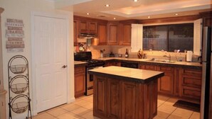 Una cocina con armarios de madera, una isla central y una puerta blanca.