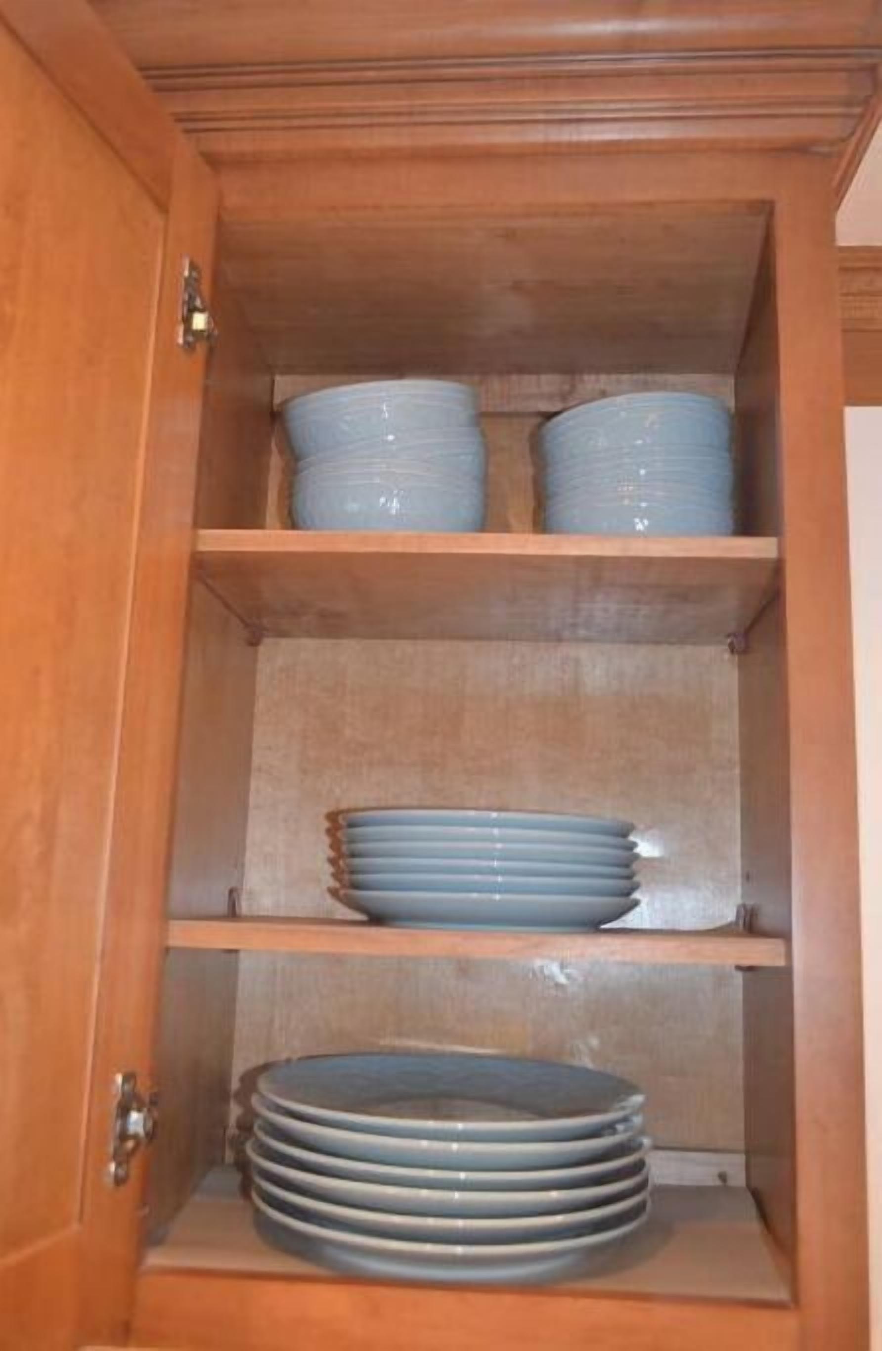 Un meuble en bois doté de plusieurs étagères, chacune contenant des piles d’assiettes bleues.
