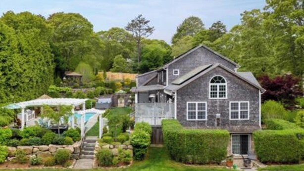 A two-story house with a stone facade, a covered patio, and a well-maintained garden. - Beautiful Estate with salt water pool  & pond with kayaks  (Oak Bluffs)