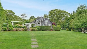 A house with a well-maintained lawn and a stone pathway leading to the entrance. - Beautiful Estate with salt water pool  & pond with kayaks  (Oak Bluffs)