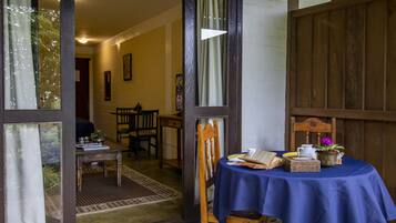 Une pièce avec une table recouverte d’une nappe bleue, des chaises en bois et une porte en bois donnant sur une autre pièce.