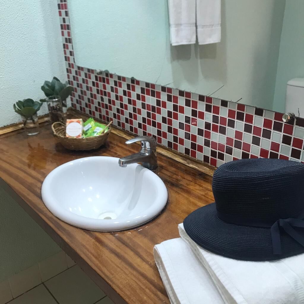 Un baño con un lavamanos blanco, una encimera de madera, un espejo y un salpicadero de azulejos.
