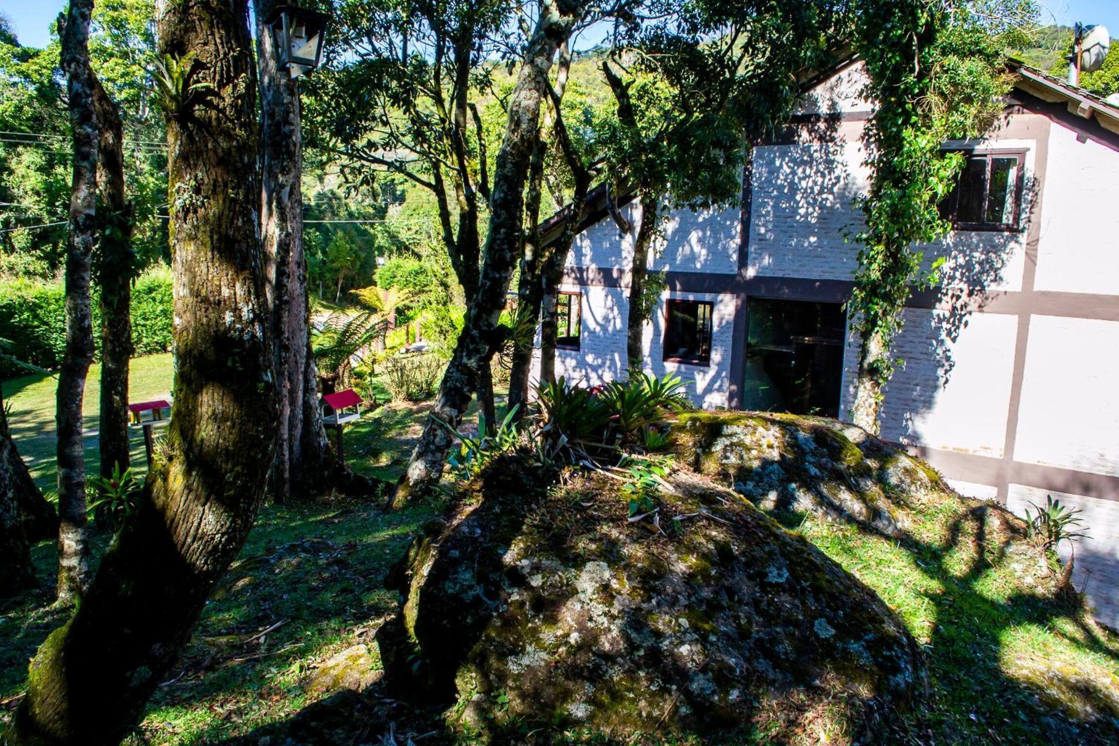 Ein Haus, umgeben von Bäumen und einem großen Felsen.