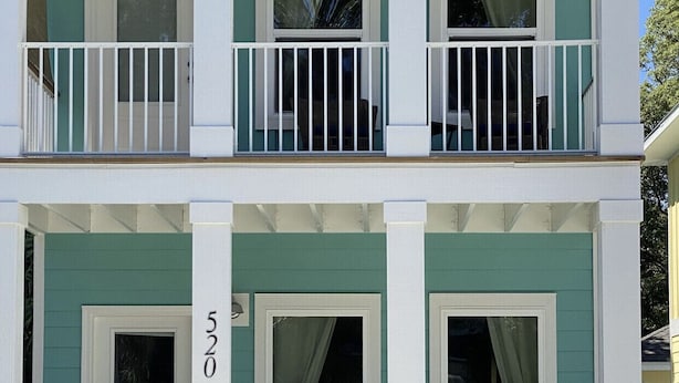 A two-story building with a green facade, white trim, and a number '520' on the door.