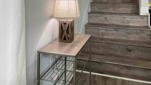 A staircase with wooden steps leading to a door, a wall-mounted lamp, and a framed picture.
