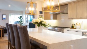 Una cocina moderna con una isla grande, iluminación colgante y electrodomésticos de acero inoxidable.