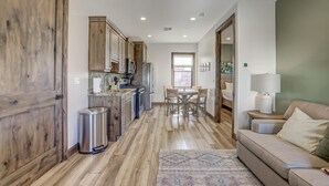 Une cuisine spacieuse avec des meubles en bois, un coin repas avec une table et des chaises, et un salon avec un canapé et une lampe.