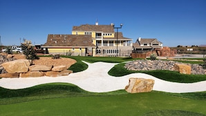 Un quartier résidentiel comprenant une grande maison à deux étages, une pelouse bien entretenue et un terrain de golf.
