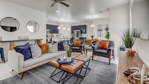 A modern living room with a sofa, armchairs, and a coffee table. There is a dining area with chairs and a table. The kitchen is visible in the background. - 5 Suites | Mini Golf | Heated Pool | Lazy River | SKY (Washington)