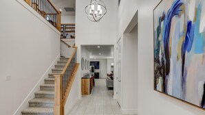 A spacious hallway with a wooden staircase, a modern kitchen, and a large abstract painting on the wall. - 5 Suites | Mini Golf | Heated Pool | Lazy River | SKY (Washington)