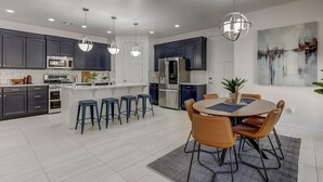 A modern kitchen with dark cabinets, stainless steel appliances, and a central island with bar stools. - 5 Suites | Mini Golf | Heated Pool | Lazy River | SKY (Washington)