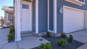 A modern two-story house with a white garage door, a small front porch, and a well-maintained garden with shrubs and gravel. - Spacious | Clean | Getaway for Two! | Sky (Washington)