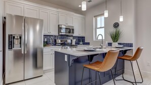 A modern kitchen with stainless steel appliances, a central island with bar stools, and a microwave above the island. - Spacious | Clean | Getaway for Two! | Sky (Washington)