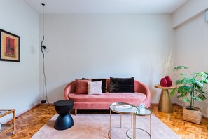 A modern living room with a pink sofa, a round coffee table, and a potted plant.