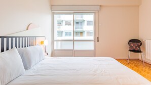 Une chambre à coucher avec un lit, une chaise, une fenêtre et un radiateur.