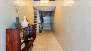 Un couloir avec une console en bois, une vitrine et un escalier menant à l’étage supérieur.