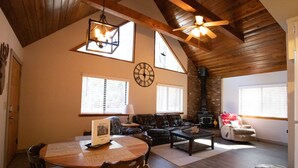 A cozy living room with a fireplace, wooden ceiling, and a dining area with a table and chairs. - Moon Creek, A lovely Cabin that is located in the Pinetop Country Club Community (Pinetop)