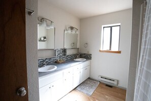 Une salle de bain avec deux lavabos, un grand miroir et une fenêtre.