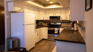 A compact kitchen with white cabinets, a stainless steel refrigerator, a built-in oven, and a microwave. - Moon Creek, A lovely Cabin that is located in the Pinetop Country Club Community (Pinetop)