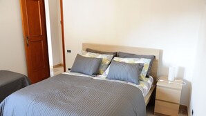 Een slaapkamer met een bed, nachtkastjes en een houten deur.
