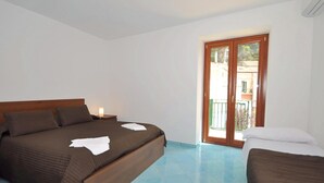 A bedroom with a large bed, a smaller bed, and a balcony with a view. - Apartment in the heart of Cetara (Cetara)