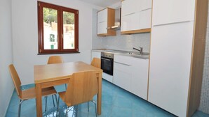 A compact kitchen with a dining table and chairs, a window, and white cabinetry. - Apartment in the heart of Cetara (Cetara)