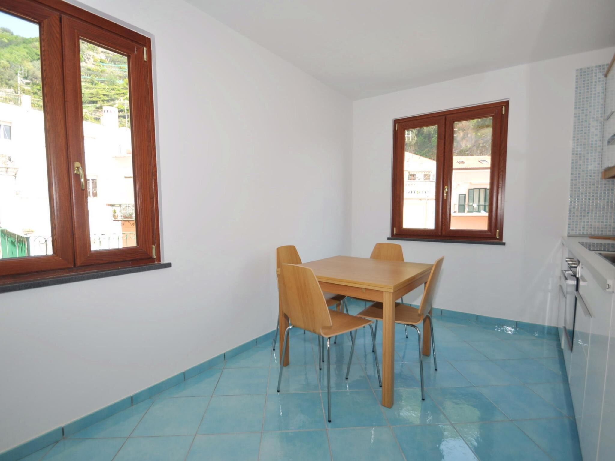 Una cocina pequeña con una mesa y sillas, una ventana y piso de baldosas.