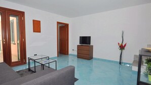A spacious living room with a grey sofa, a glass coffee table, a wooden TV stand, and a tiled floor. - Apartment in the heart of Cetara (Cetara)