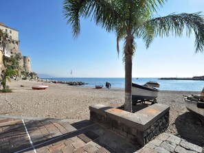 A beach with boats, a palm tree, and a historic building. - B&B in the heart of Cetara - double room (Cetara)