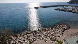 Un port de plaisance situé sur la côte, avec des bateaux amarrés, une rive rocheuse et une vue dégagée sur la mer.