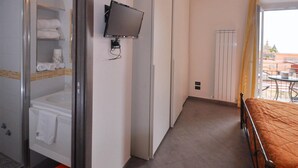 A hotel room with a shower, a bed, a TV mounted on the wall, and a view of the outside balcony. - B&B in the heart of Cetara - Standard Double room (Cetara)