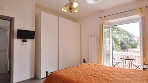 A bedroom with a bed, a television on the wall, a sliding door, and a balcony with chairs. - B&B in the heart of Cetara - Standard Double room (Cetara)