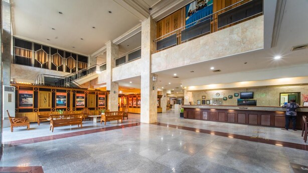 A spacious lobby with a reception desk, seating area, and a staircase leading to an upper level.